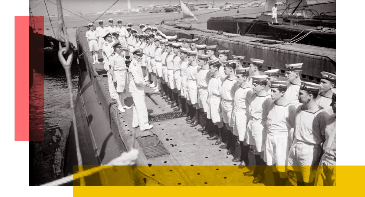 WW2 Sailors stand atop a submarine in the dock