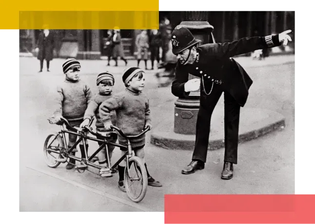 Three small boys with a trandem bike are spoken to by a police officer