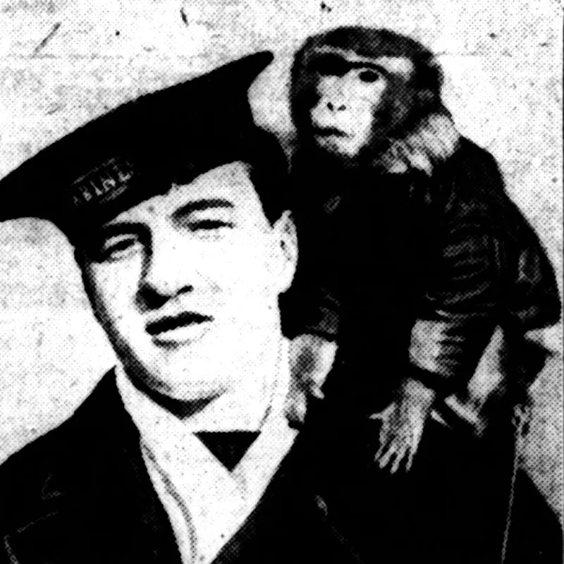A Navy sailor poses with a pet monkey