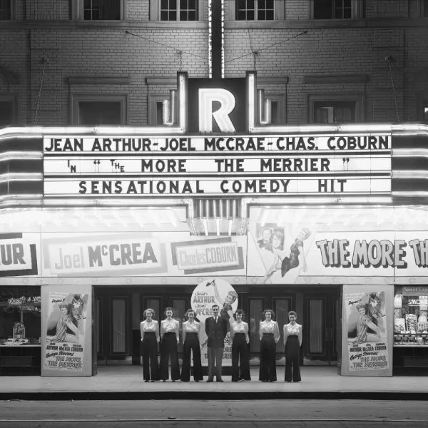 A group of people standing in front of a movie theatre